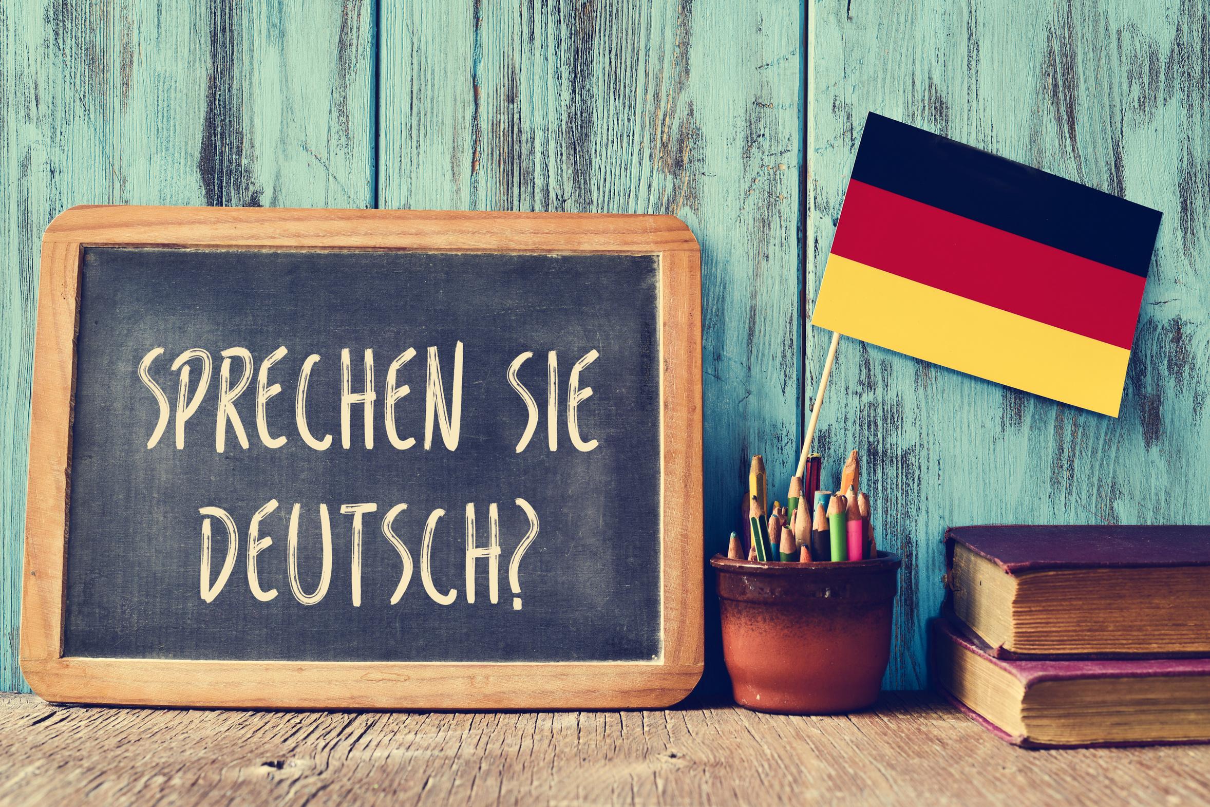 'Do you speak German?' written on a blackboard next to the national flag of Germany